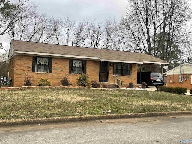 ranch-style home with entry steps, a front yard, an attached carport, and brick siding