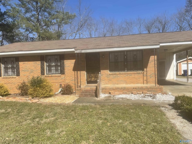 view of front facade featuring a carport, brick siding, a front yard, and driveway