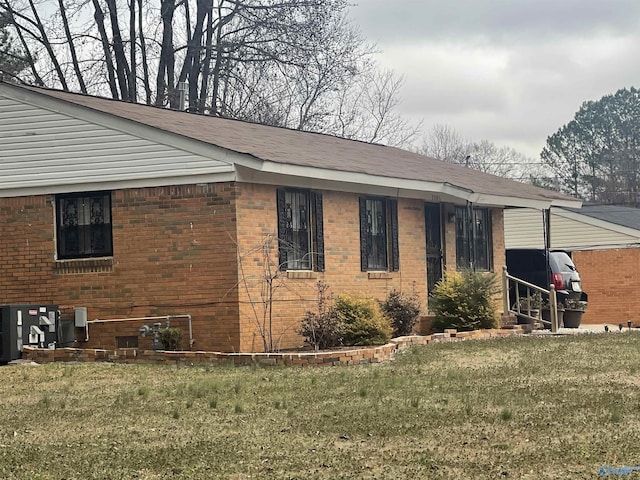 view of property exterior featuring brick siding, a yard, and central AC