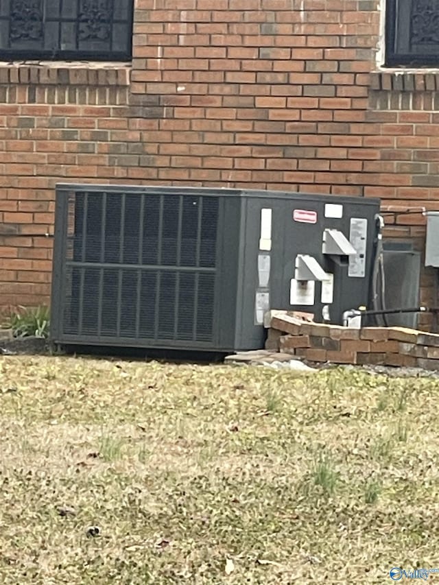 exterior details featuring central AC unit and brick siding