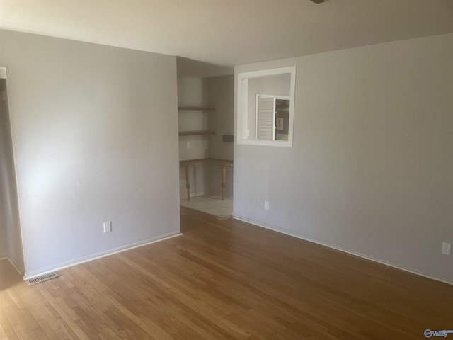 empty room with visible vents, baseboards, and wood finished floors