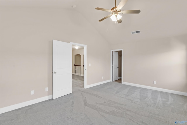 carpeted empty room with visible vents, baseboards, high vaulted ceiling, arched walkways, and ceiling fan