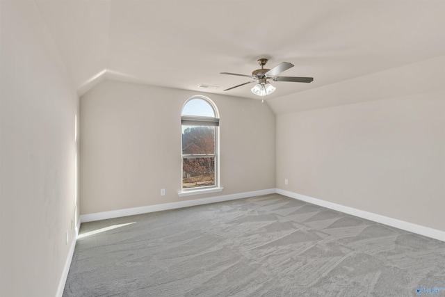 carpeted spare room featuring lofted ceiling, visible vents, baseboards, and ceiling fan