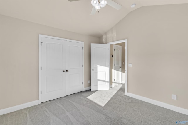 unfurnished bedroom with lofted ceiling, a ceiling fan, a closet, carpet flooring, and baseboards