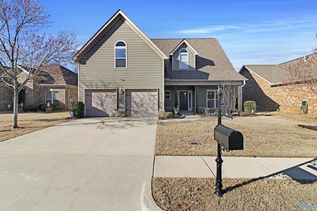 traditional-style house featuring a garage, roof with shingles, and concrete driveway