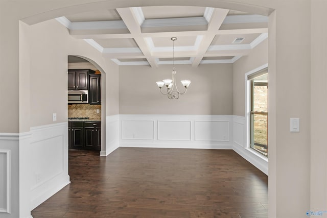 unfurnished dining area with visible vents, dark wood finished floors, beam ceiling, an inviting chandelier, and coffered ceiling