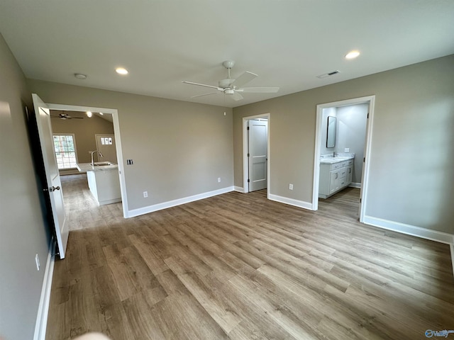 unfurnished bedroom with connected bathroom, ceiling fan, sink, and light hardwood / wood-style flooring