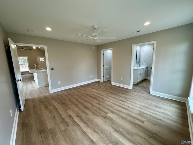 unfurnished bedroom featuring a walk in closet, ensuite bath, ceiling fan, light hardwood / wood-style floors, and a closet