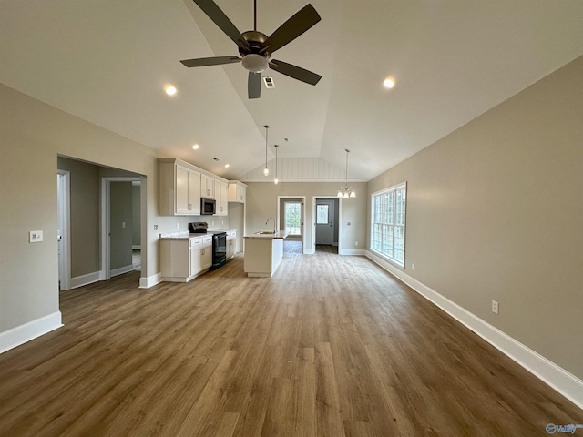 unfurnished living room featuring hardwood / wood-style floors, ceiling fan with notable chandelier, sink, and high vaulted ceiling