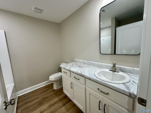 bathroom with a washtub, hardwood / wood-style floors, vanity, and toilet