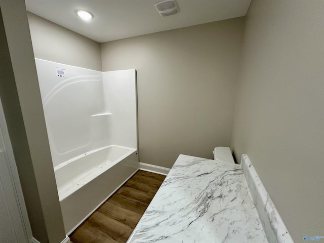 bathroom with shower / tub combination, hardwood / wood-style flooring, and toilet