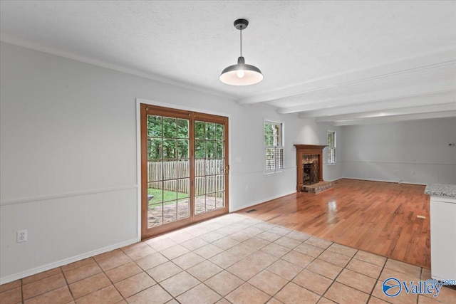 tiled spare room with a brick fireplace and beam ceiling