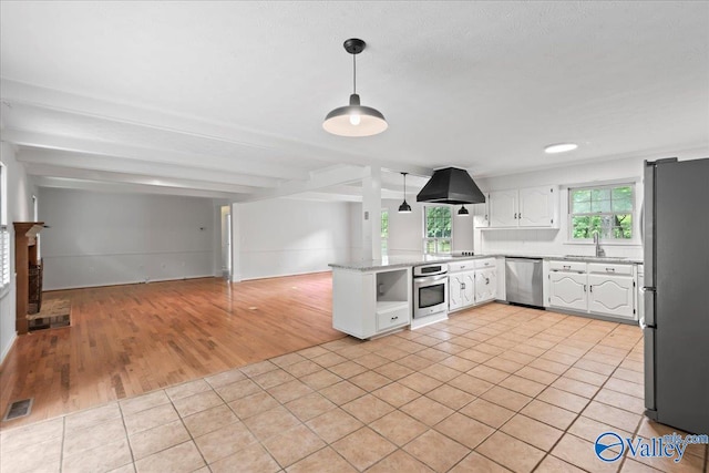 kitchen with light tile patterned flooring, beam ceiling, white cabinets, stainless steel appliances, and island range hood