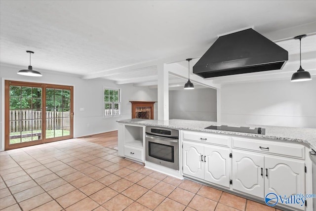 kitchen featuring black electric stovetop, oven, decorative light fixtures, and island range hood