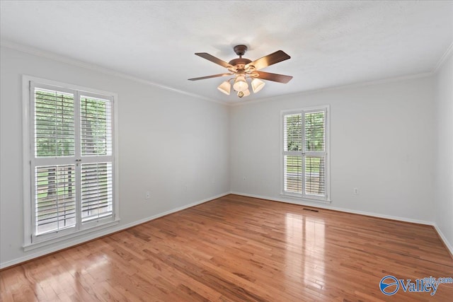 empty room featuring plenty of natural light, crown molding, light wood-type flooring, and ceiling fan