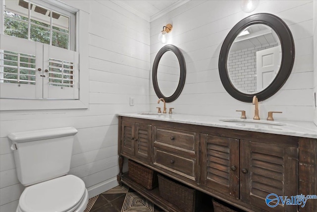 bathroom featuring double vanity, tile patterned flooring, crown molding, toilet, and wood walls