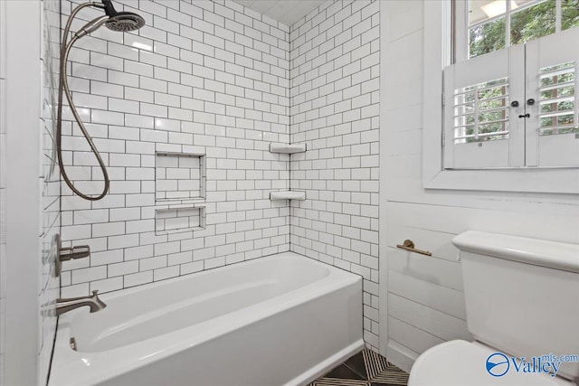 bathroom featuring toilet, tile patterned floors, and tiled shower / bath combo