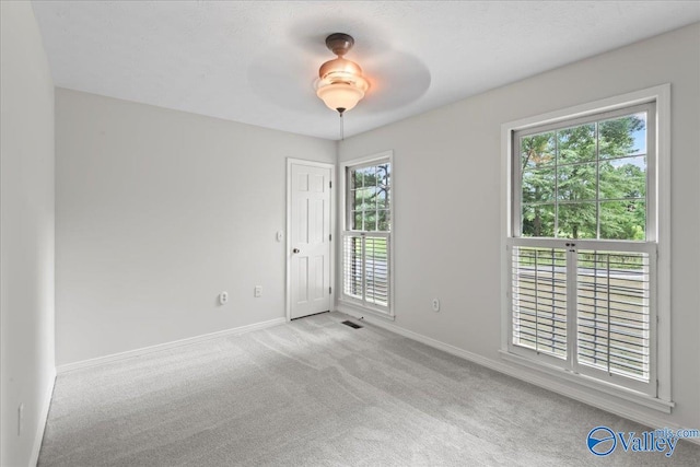 carpeted empty room featuring a healthy amount of sunlight and ceiling fan