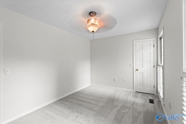 carpeted spare room featuring a wealth of natural light and ceiling fan