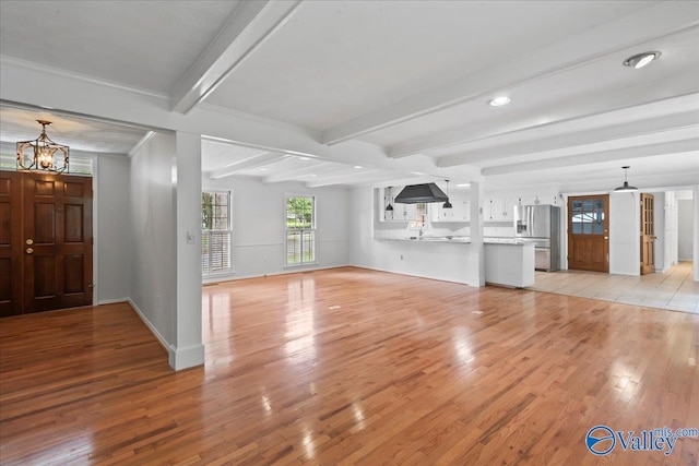 unfurnished living room with a notable chandelier, light tile patterned flooring, and beam ceiling