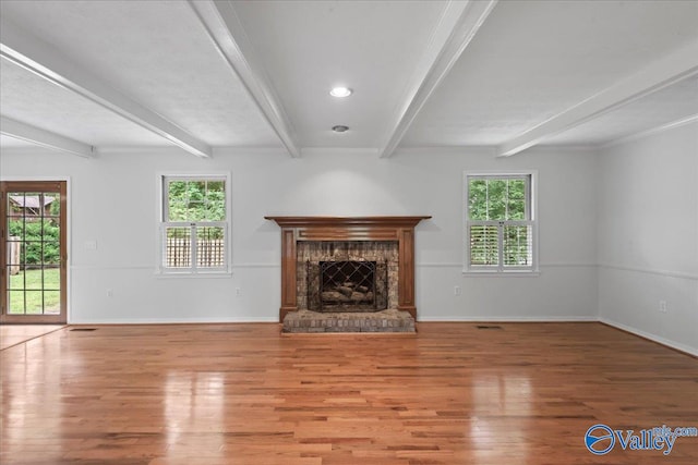 unfurnished living room with beamed ceiling, hardwood / wood-style flooring, and plenty of natural light