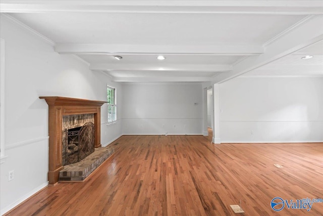 unfurnished living room featuring beam ceiling, a brick fireplace, and hardwood / wood-style floors