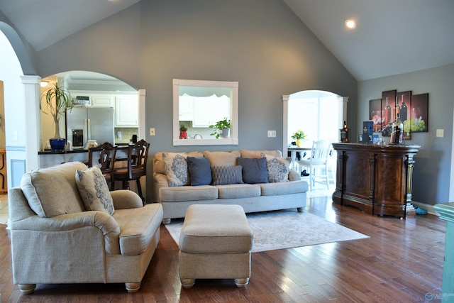 living room with high vaulted ceiling, hardwood / wood-style floors, and ornate columns