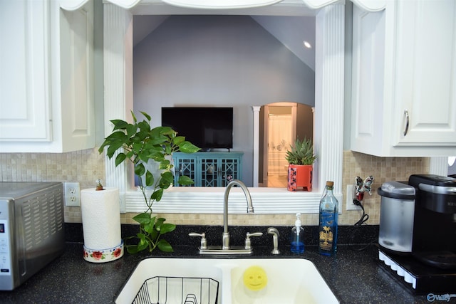 kitchen with decorative backsplash, sink, white cabinets, and lofted ceiling