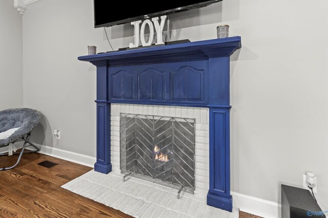 interior details with visible vents, a fireplace, baseboards, and wood finished floors