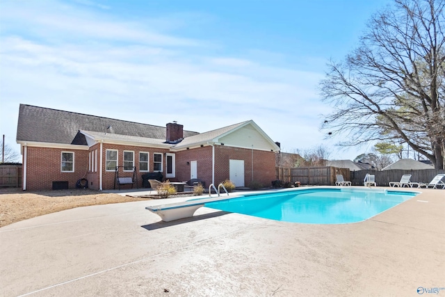 view of swimming pool featuring a fenced in pool, a fenced backyard, a patio, and a diving board