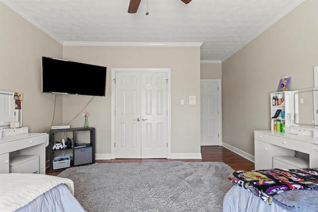 bedroom featuring a closet, ornamental molding, ceiling fan, wood finished floors, and baseboards