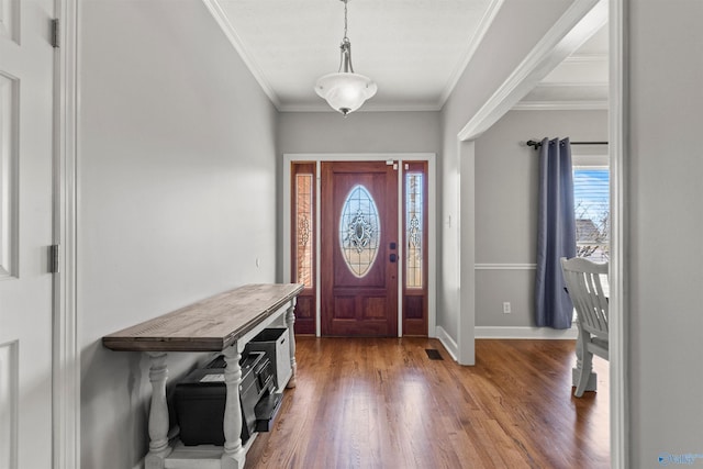 foyer entrance with baseboards, wood finished floors, visible vents, and crown molding