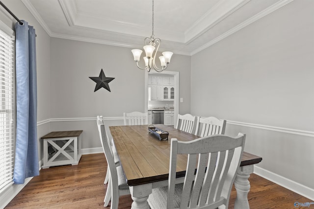 dining area featuring crown molding, a tray ceiling, a chandelier, and wood finished floors