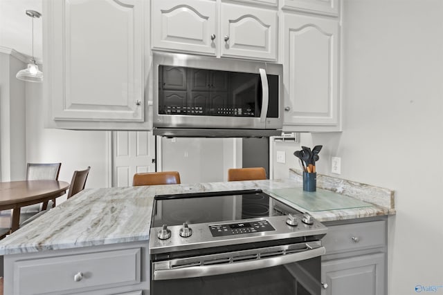 kitchen with stainless steel appliances, white cabinetry, decorative light fixtures, and light stone counters