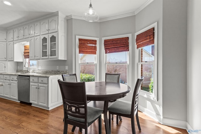 dining area with a wealth of natural light, baseboards, ornamental molding, and wood finished floors