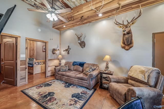 living area featuring beamed ceiling, a towering ceiling, a ceiling fan, wood ceiling, and concrete floors