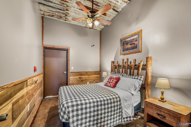 bedroom featuring wood walls, a ceiling fan, and wainscoting