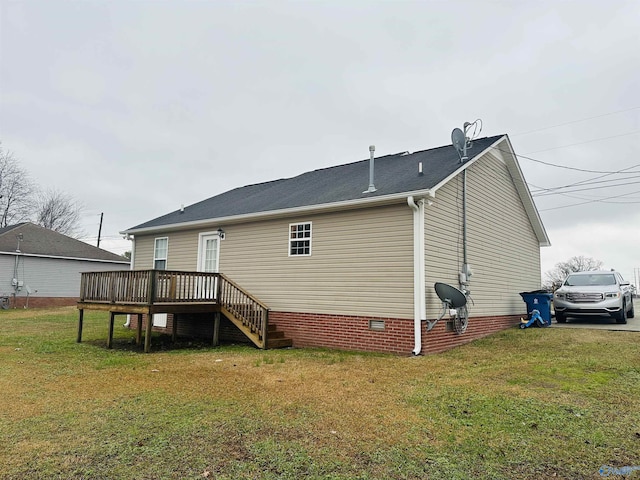 rear view of property featuring a wooden deck and a lawn