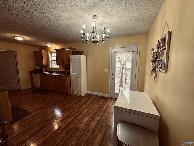 unfurnished dining area with dark hardwood / wood-style flooring, sink, a textured ceiling, and an inviting chandelier