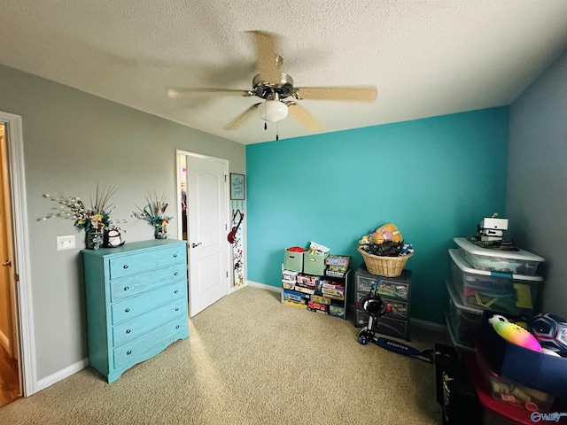 recreation room with ceiling fan, carpet floors, and a textured ceiling