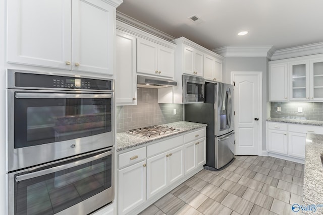 kitchen featuring light stone countertops, white cabinetry, stainless steel appliances, and tasteful backsplash