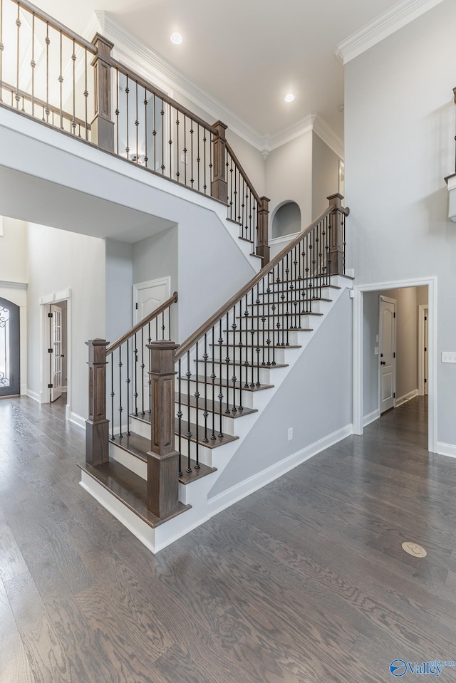 staircase featuring hardwood / wood-style flooring, crown molding, and a high ceiling