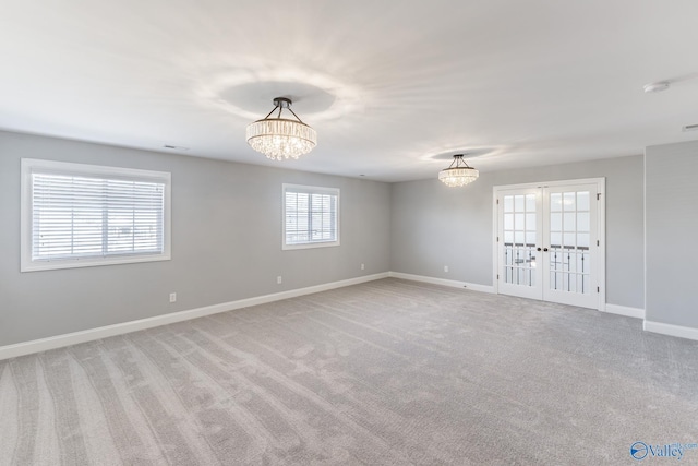 carpeted empty room with french doors and an inviting chandelier