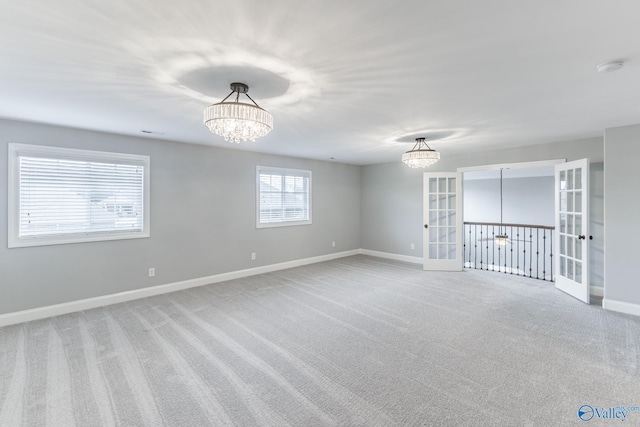 spare room featuring carpet, french doors, and a chandelier