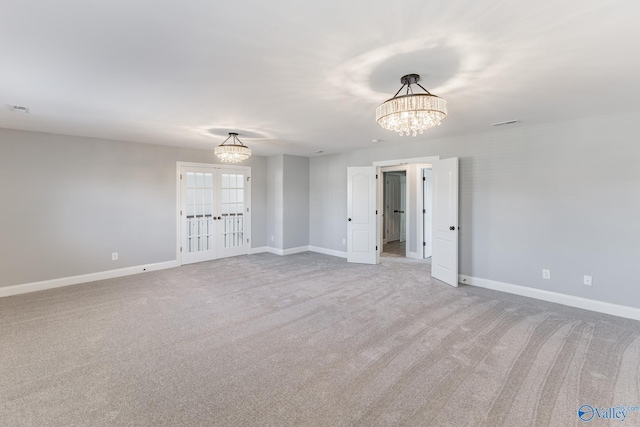 carpeted spare room with french doors and a notable chandelier