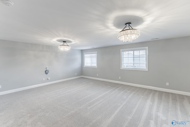 empty room featuring carpet and a notable chandelier