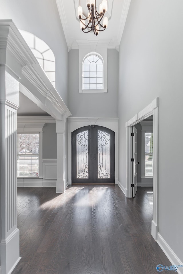 foyer featuring crown molding, french doors, a healthy amount of sunlight, and a notable chandelier