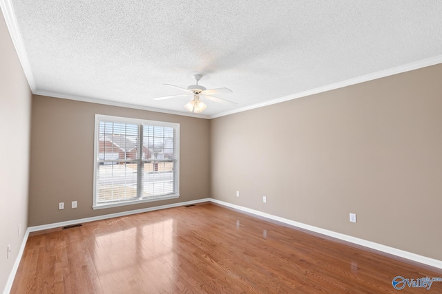 spare room with visible vents, crown molding, baseboards, ceiling fan, and wood finished floors