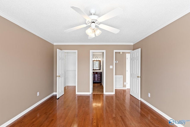 unfurnished bedroom with visible vents, crown molding, baseboards, and wood finished floors