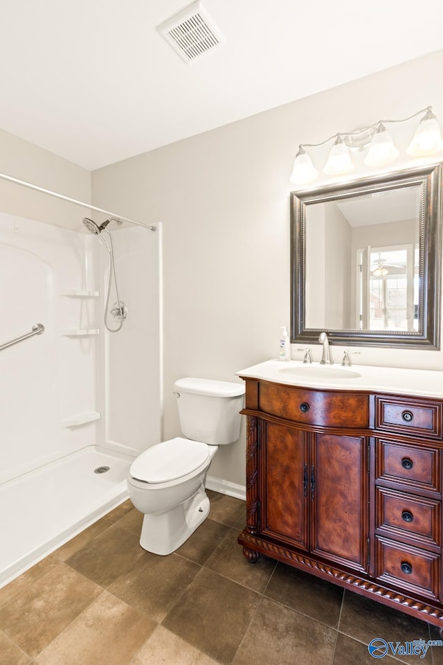 full bath featuring vanity, baseboards, visible vents, walk in shower, and toilet